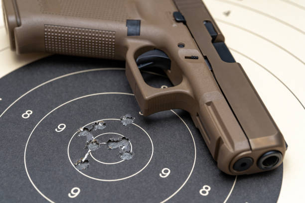 istock Sand colored pistol on the paper target with holes from bullets 1752261238
