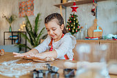 Smiling girl making dough for Christmas cookies