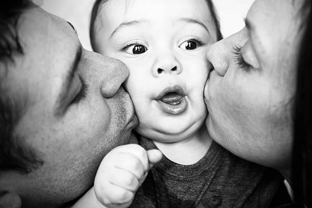 Baby Getting Kissed by Parents stock photo