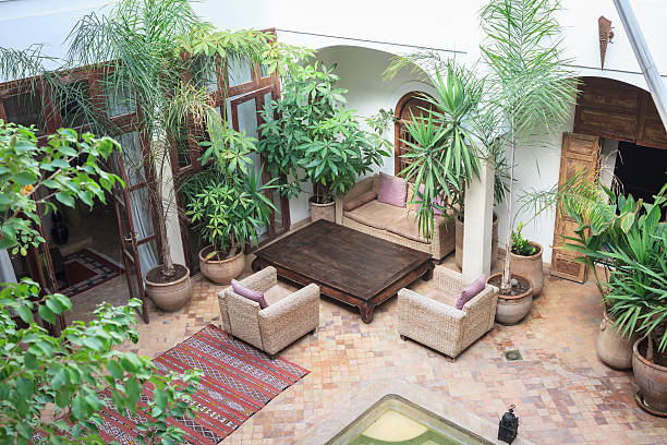 Patio of a Moroccan Riad in Marrakech Traditional Moroccan house with an interior courtyard with plants, carpet, armchairs and swimming pool. marrakesh riad stock pictures, royalty-free photos & images