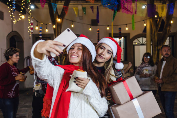 posada mexicana, coppia messicana di amici che scatta un selfie fotografico con i telefoni cellulari durante la celebrazione del natale in messico - pinata mexico christmas mexican culture foto e immagini stock
