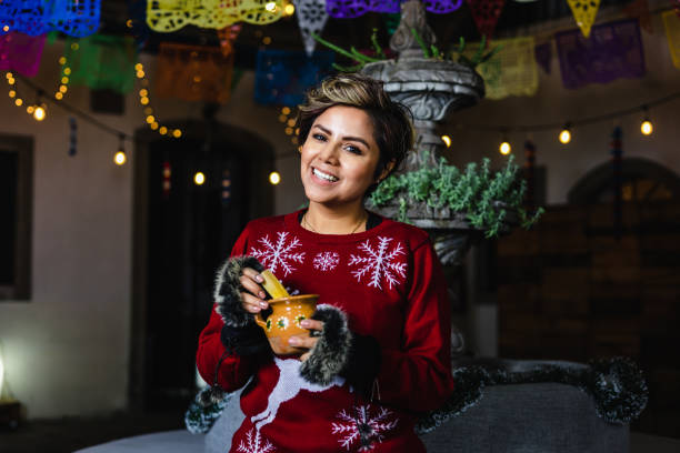 portrait d’une jeune femme hispanique tenant une tasse de punch aux fruits lors d’une fête traditionnelle posada pour noël au mexique amérique latine - pinata mexico christmas mexican culture photos et images de collection