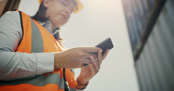 Woman, engineer and cellphone for communication, site project and shipping container. Logistics, cargo and serious for email, technology and texting for networking, contractor or freight distribution