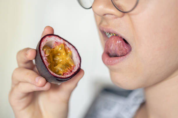 little girl eats passion fruit, mouth close-up. - healthy eating profile tropical fruit fruit imagens e fotografias de stock