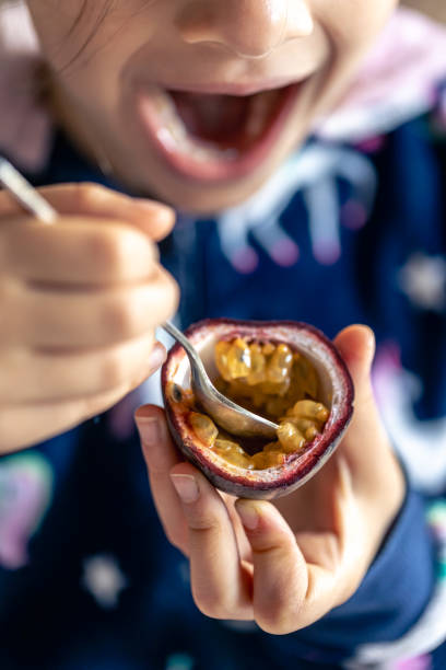 little girl eats passion fruit, mouth close-up. - healthy eating profile tropical fruit fruit imagens e fotografias de stock