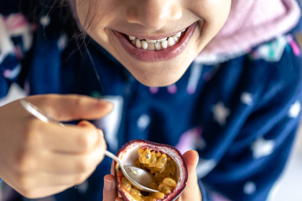 little girl eats passion fruit, mouth close-up. - healthy eating profile tropical fruit fruit imagens e fotografias de stock