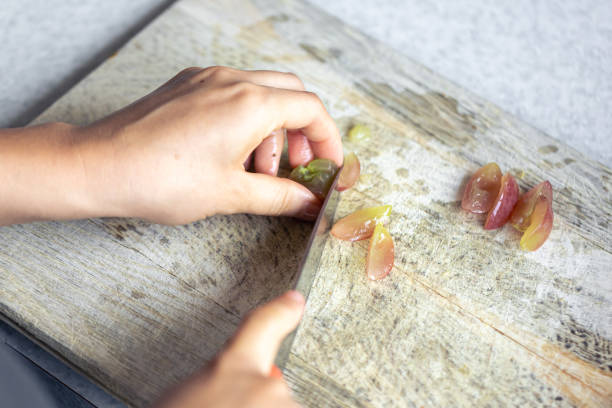 A woman cuts grapes on a cutting board.