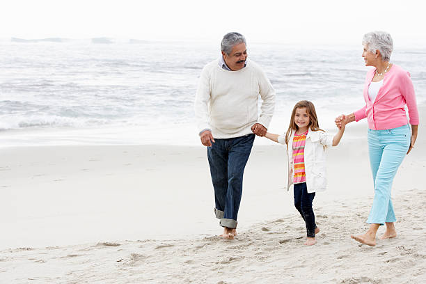 istock Grandparents Walking Along Beach With Granddaughter 175228973