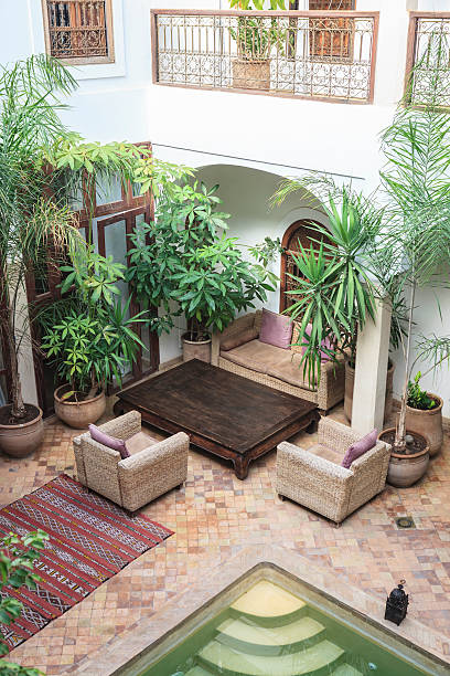 Patio of a Moroccan Riad in Marrakech Traditional Moroccan house with an interior courtyard with plants, carpet, armchairs and swimming pool. marrakesh riad stock pictures, royalty-free photos & images