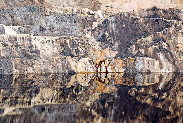 Berkeley Pit copper mine reflected in polluted water Berkeley Pit copper mine reflected in polluted water at environmental clean-up site in Butte MT copper mine photos stock pictures, royalty-free photos & images