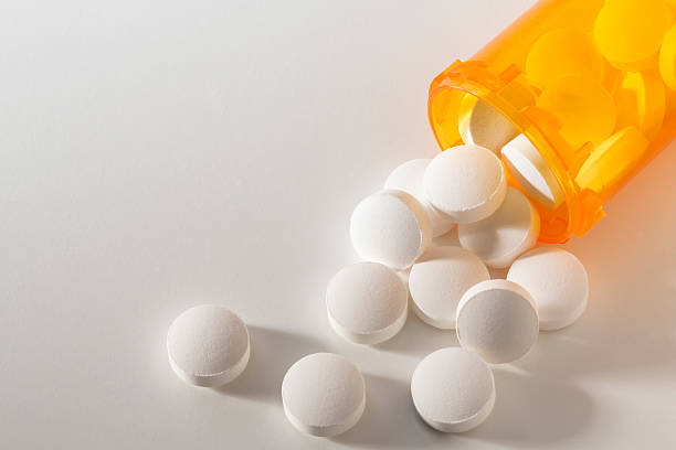 Prescription Medicine Spilling From an Open Bottle Prescription medication spilling from an open bottle onto a white surface. generic description stock pictures, royalty-free photos & images