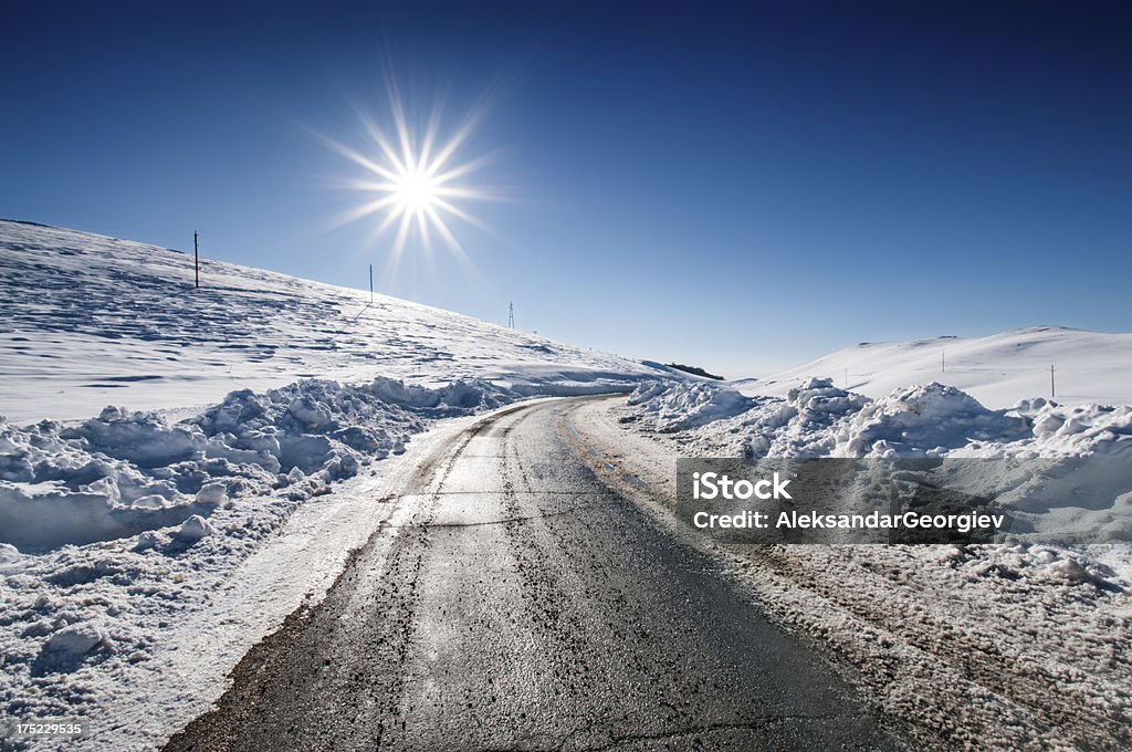 Vuota strada circondata da neve in inverno al tramonto - Foto stock royalty-free di Ambientazione esterna