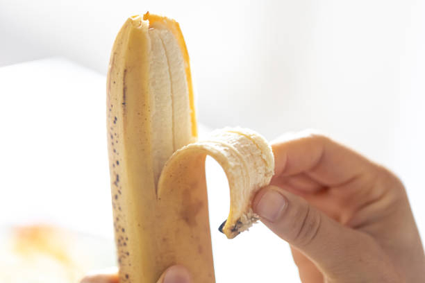 istock A woman peels a ripe banana, close-up. 1752296628