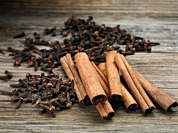 Cinnamon Sticks Close up of Cinnamon Sticks with Whole Clove on Wooden Table. cinnamon sticks cloves stock pictures, royalty-free photos & images
