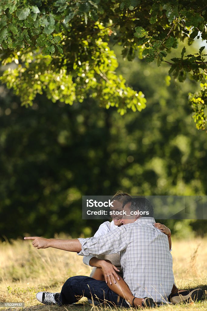 lifestyle young couple sitting on grass and showing with finger. 20-29 Years Stock Photo