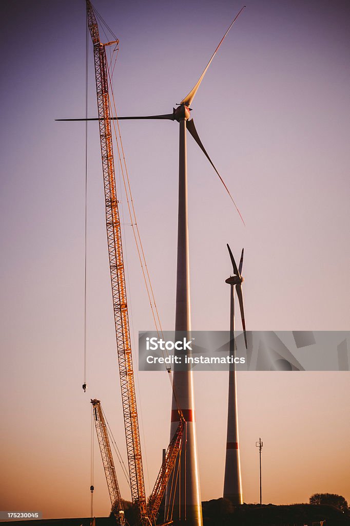 Dos turbinas eólicas con una grúa de la construcción en sunset - Foto de stock de Aerogenerador libre de derechos