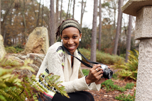 Teenage girl holding an old fashion SLR camera learning photography.