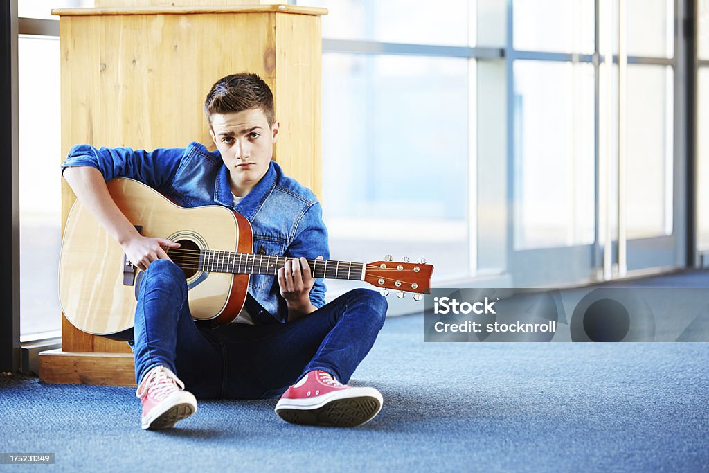 Cool nastolatek z Gitara siedzi na dywanie w korytarzu - Zbiór zdjęć royalty-free (20-29 lat)