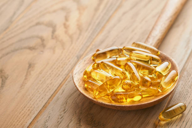 istock Close up capsules with Vitamin D, E or Omega 3,6,9 fatty acids in bottle on old wooden backgrounds. Food supplement oil filled fish oil. Natural supplements for healthy good life concept. Banner. 1752318708
