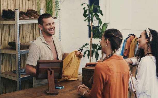 mode, kassierer und mann im geschäft mit kunden, verkauf von kleinunternehmen mit freundlichem lächeln an der kasse und beim einkaufen. kleidung, glückliche frauen an der kasse im secondhand-laden, zahlung im einzelhandel und menschen in der boutique. - boutique stock-fotos und bilder