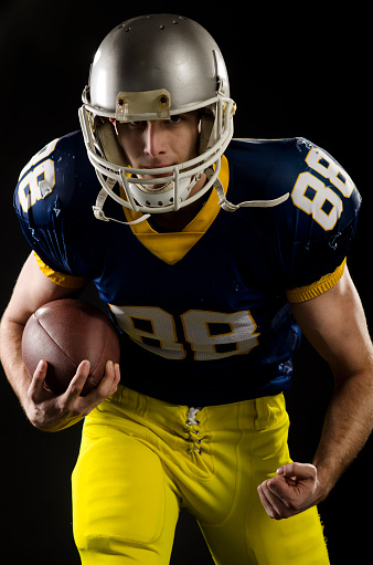 High school american football player, over black background.