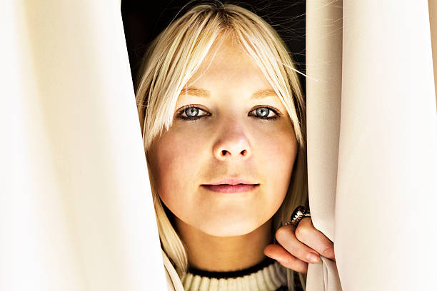 istock I see you! Cute but serious blonde peeping through curtains 175232932