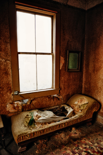 Old Bedroom Chaise Lounge In Abandoned Mining Town Home.  The walls have wonderfully textured wallpaper.  There is a big window for light and an old empty picture frame.  Tiled floors.  Small grain.