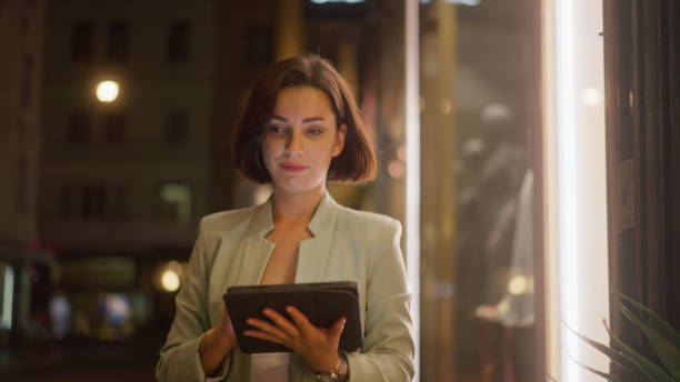 istock Smiling young businesswoman doing remote work with digital device while walking in city 1752330642
