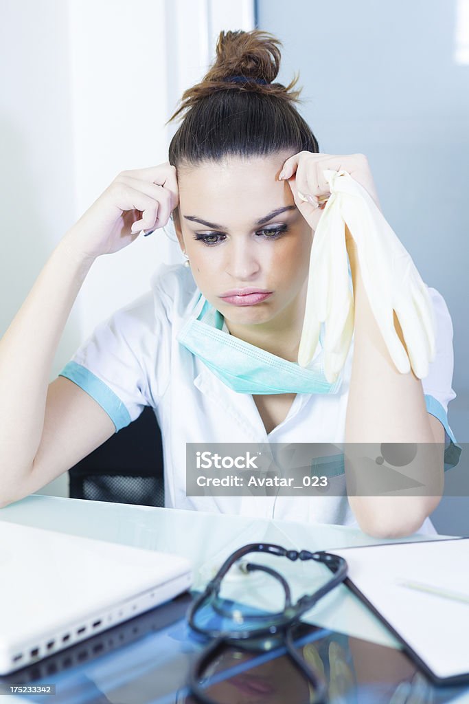 Female doctor "Female doctor holding a head and making a face,to much work for today.." 20-29 Years Stock Photo