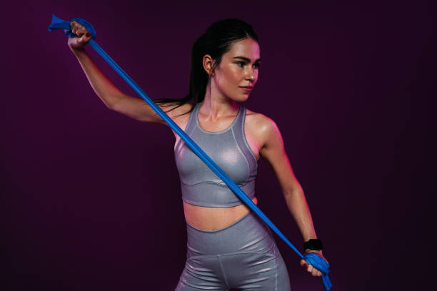 istock Slim woman exercising with resistance band against magenta backdrop 1752335573