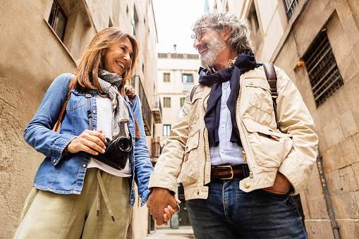 Lovely senior pensioner tourist couple holding hands standing in city street during vacation. Lifestyle retirement and holidays concept