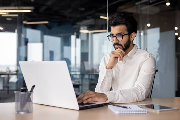 istock A young Indian man is working in the office on a laptop, thoughtfully and seriously looking at the screen. Reads information and news, received an email 1752338534