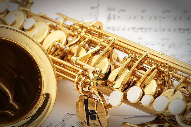 альт-саксофон с нотные листы в фоне - мягкий джаз стоковые фото и изображения