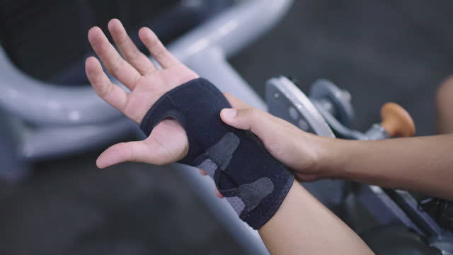 A guy with wrist pain wearing a wrist support at the gym