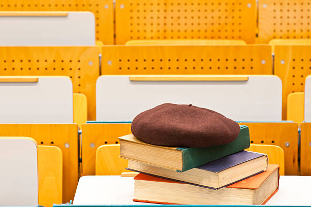 Old books with a basque beret (French headwear) on top on a pull out table in a university hall. Copy space.