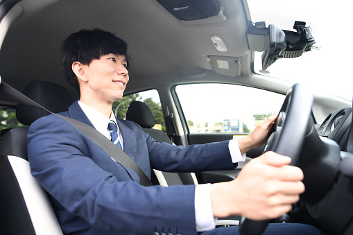Asian male driver wearing a suit and driving