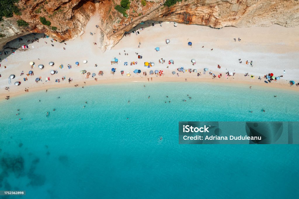 Aerial view of people on beautiful beach by mountain in Lefkada, Greece Drone view of people on sunny beach by turquoise sea Aerial View Stock Photo