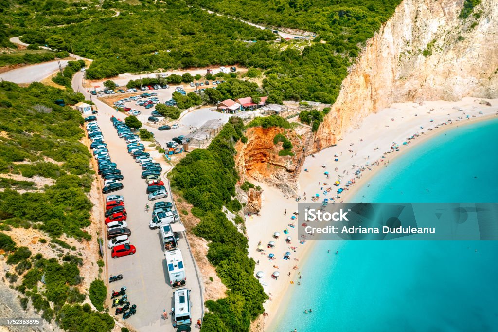 Aerial view of parking by beautiful beach and mountain in Lefkada, Greece Drone view of cars in parking by sunny beach and turquoise sea Aerial View Stock Photo