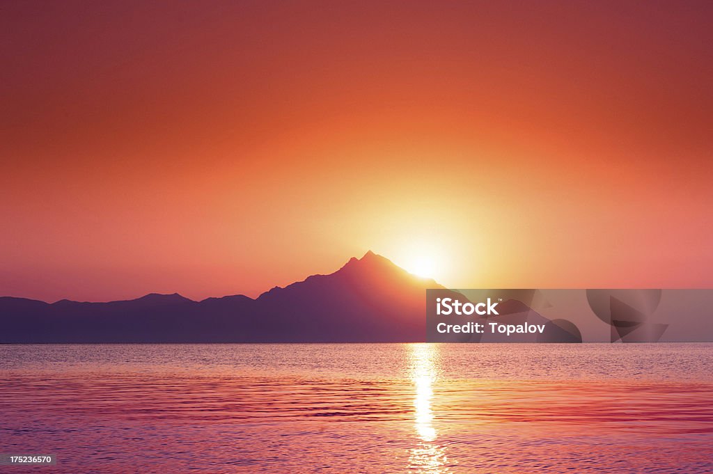Romantic sky Beautiful vibrant sunrise over sea behind mountain Backgrounds Stock Photo