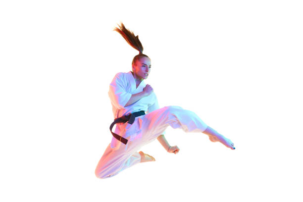 Young female karate fighter, karate master jumping, training in action isolated over white studio background. Concept of professional sport, recreation, art, hobby, culture. Copy space for ad, text.