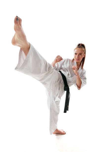 maître combattant de tae kwon do ceinture noire en uniforme montre une pose de coup de pied haut isolée sur fond blanc. - martial arts women tae kwon do black belt photos et images de collection