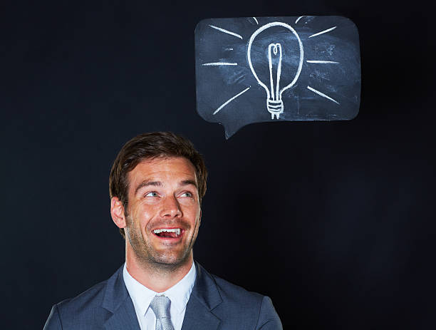 He's got a great idea A handsome businessman looking excited with a lightbulb drawn on the chalkboard above him man with a light bulb over his head stock pictures, royalty-free photos & images