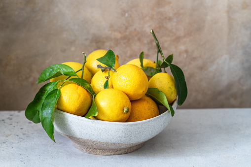 Fresh ripe lemons with green leaves on wooden table