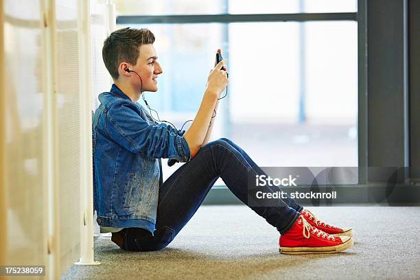 Cool Teenager Listening To Music Whilst Texting On Mobile Stock Photo - Download Image Now