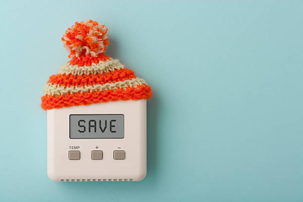 SAVE on digital room thermostat with wooly hat The word SAVE on a digital room thermostat wearing wooly hat. energy management stock pictures, royalty-free photos & images