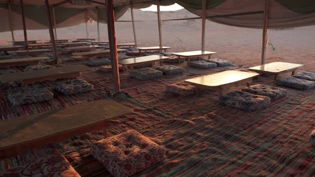 Lunch tables for tourists inside bedouin tent at sunset in a camp in the desert