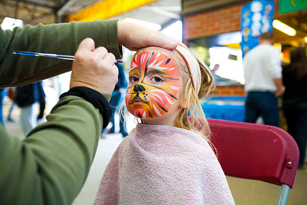 Face painting A pretty girl sits patiently while having her face painted at a petting farm cat face paint stock pictures, royalty-free photos & images