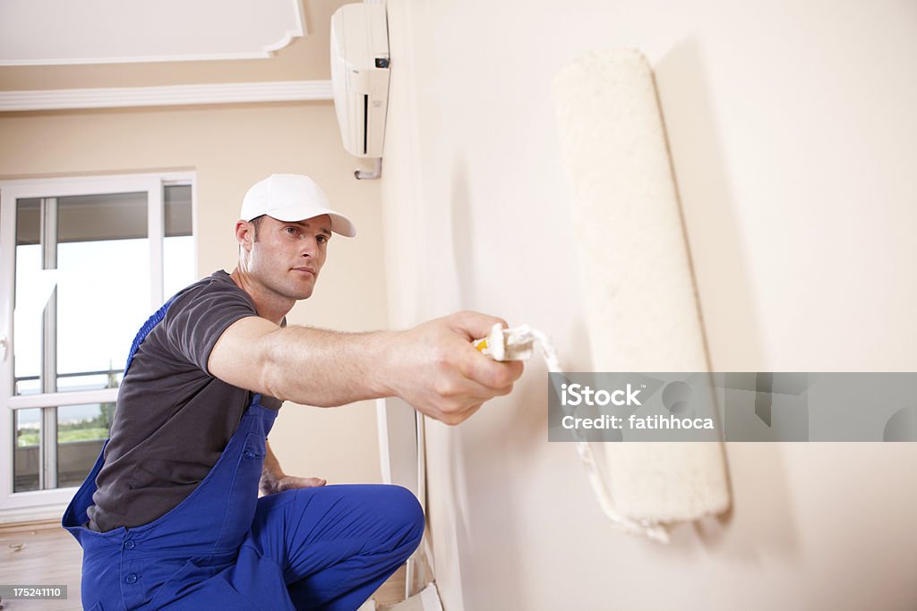 House painter primes interior wall House painter is painting on the wall. House Painter Stock Photo