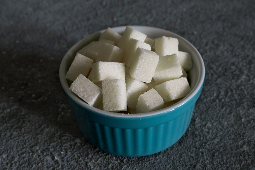Refined sugar pieces in a bowl, close-up, culinary raw material