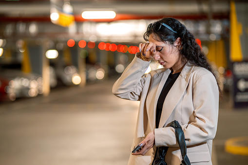 Businesswoman having headache due to stress in parking garage after work